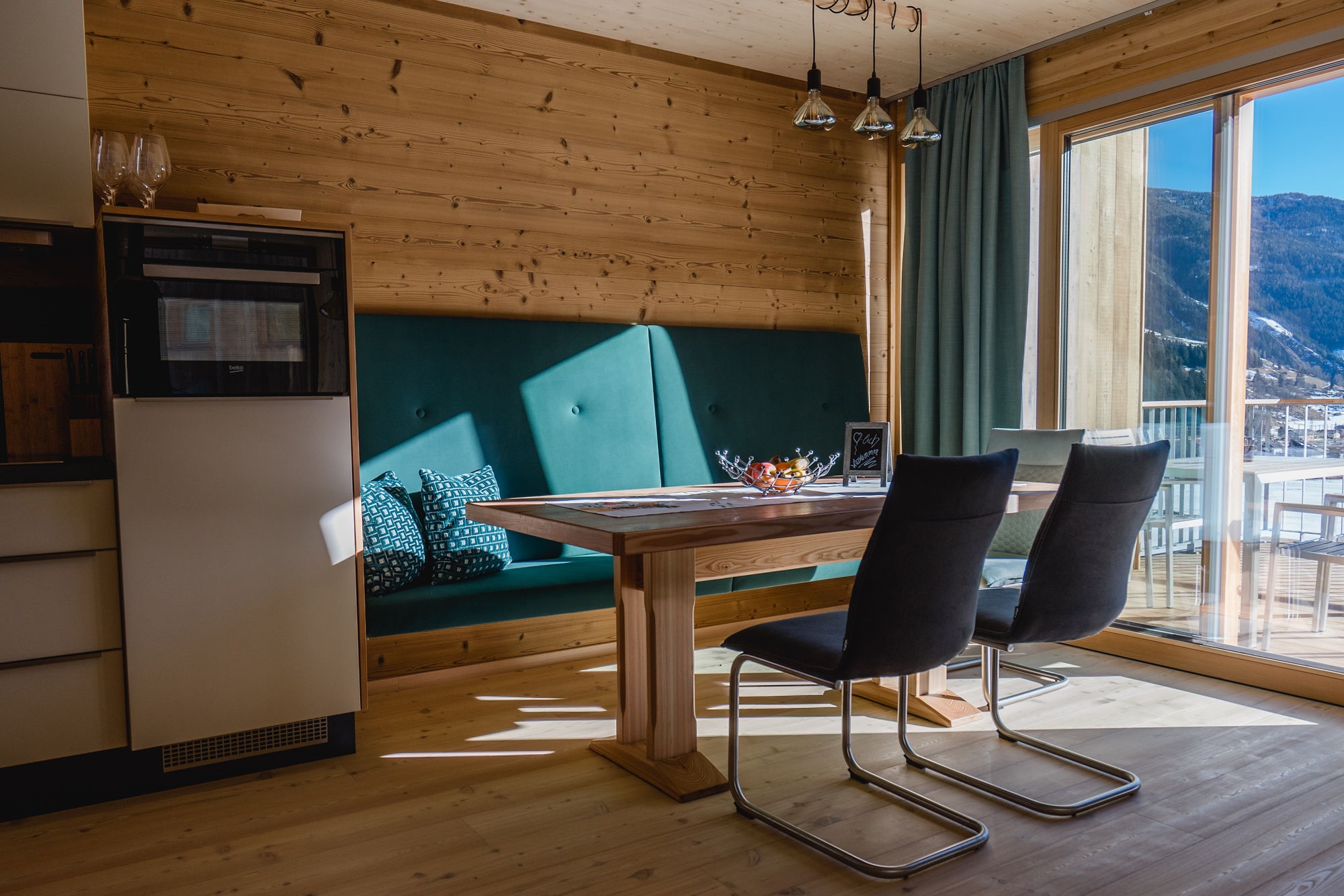Essbereich mit Sitzbank, Esstisch und Panoramafenster mit Bergblick