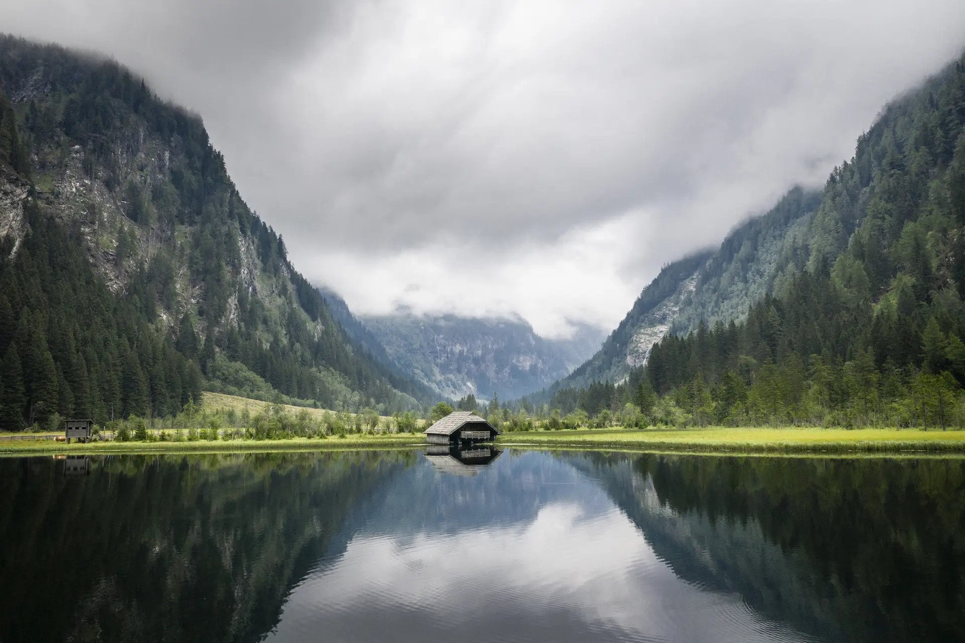 Bergsee mit Spiegelung und nebelverhangenen Bergen