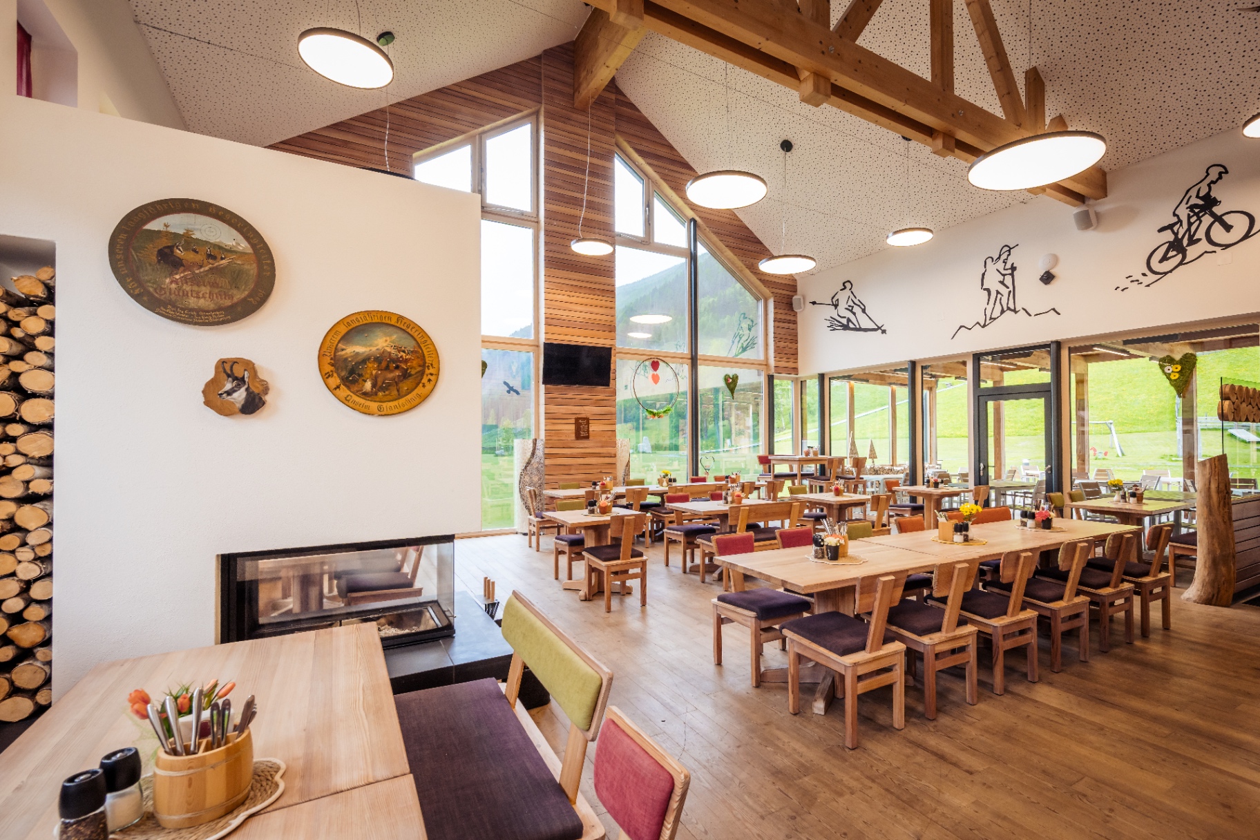 Restaurant-Innenraum mit Kamin, hoher Holzdecke und Panoramafenstern